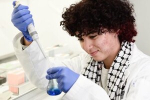 Bessan Amer using a syringe to place a sample into a test tube