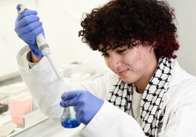 Bessan Amer using a syringe to place a sample into a test tube